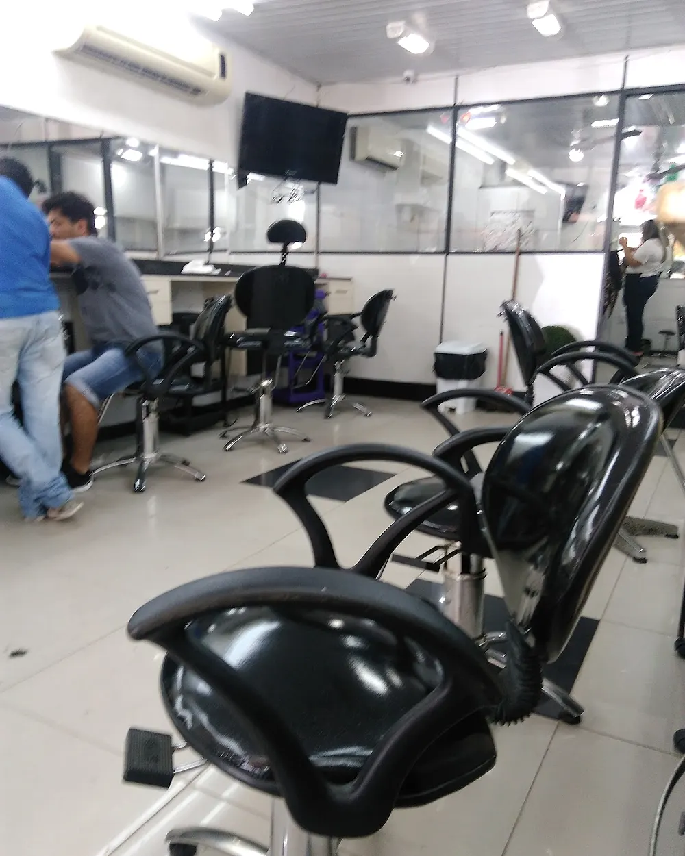 Interior do salão com cadeiras pretas, espelhos e bancadas