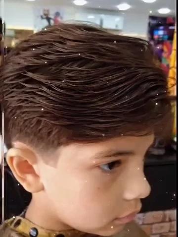 Menino de perfil com degradê nas laterais e topete penteado
