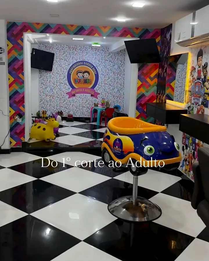Espaço kids com piso xadrez preto e branco, cadeirinha em formato de carrinho amarelo e paredes coloridas