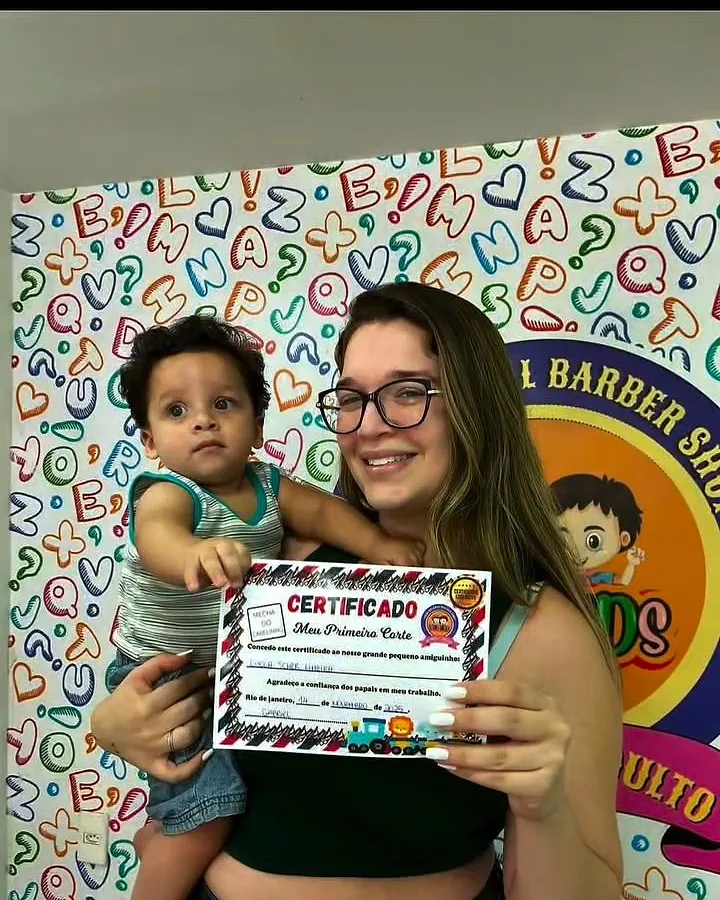 Mãe com o bebê no colo mostrando o certificado do primeiro corte