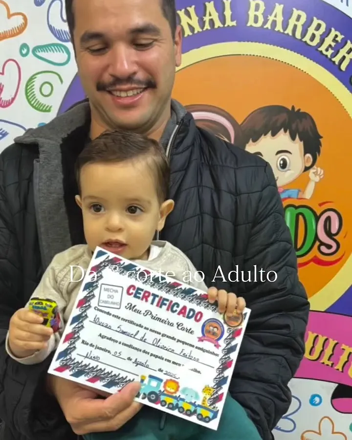 Pai segurando o bebê com o certificado do primeiro corte