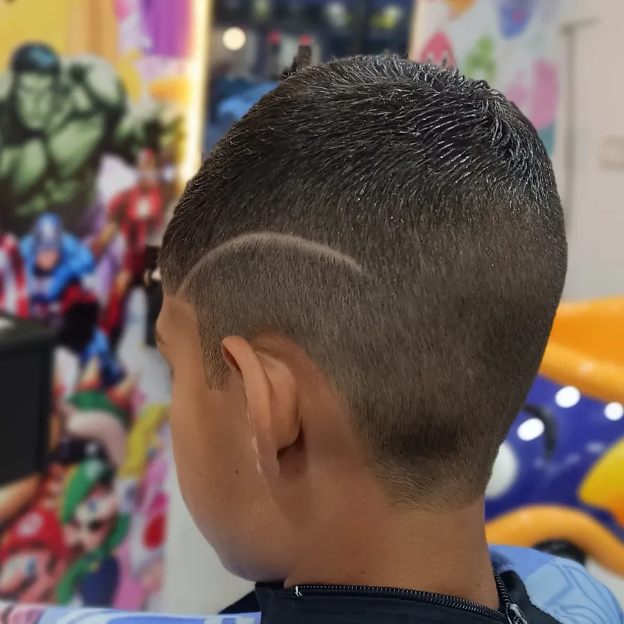 Menino de costas com degradê e risco, com pôster de super-heróis ao fundo